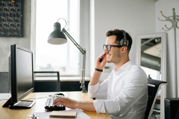 Friendly person sitting at computer on a phone conversation.